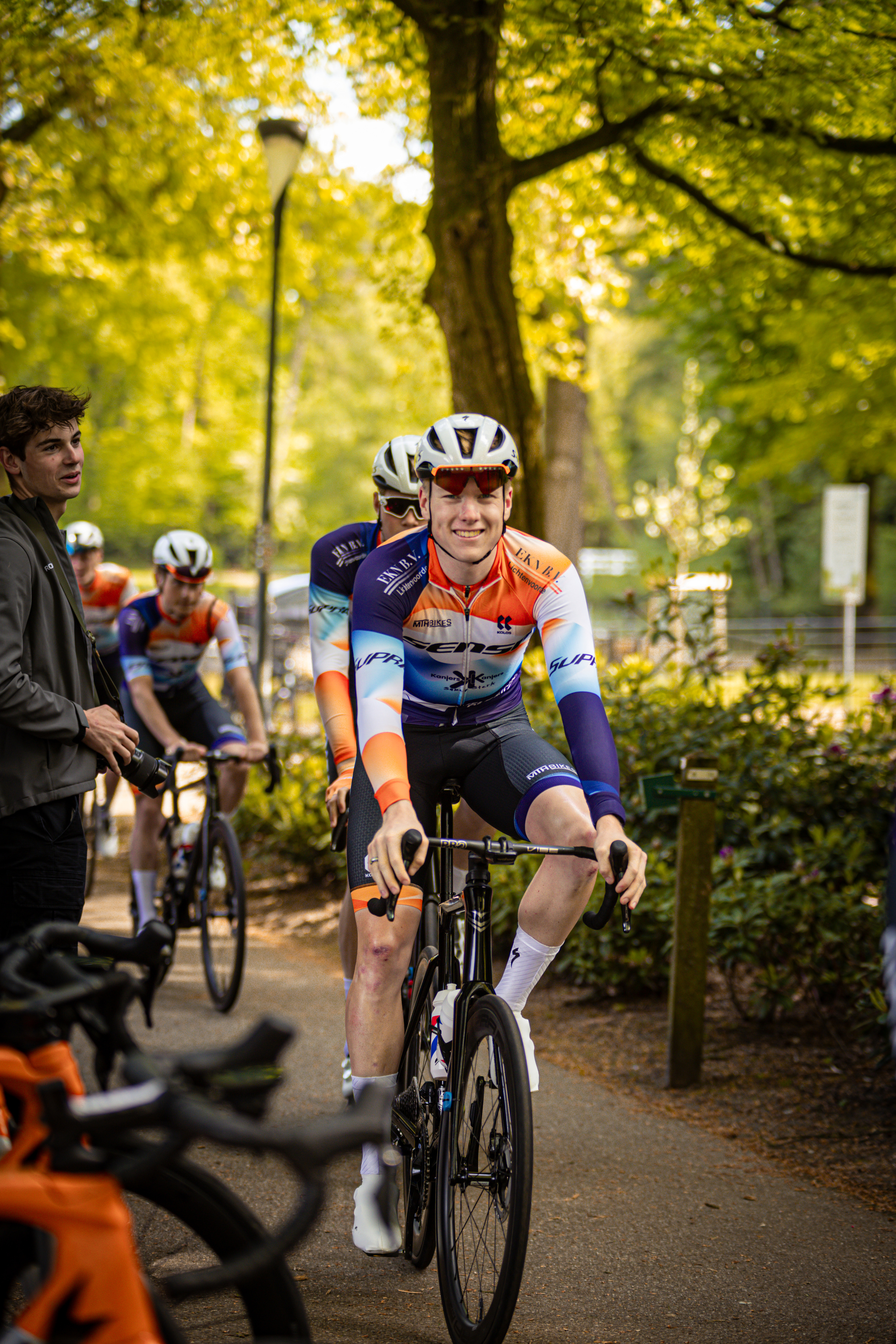 A man wearing a shirt with the letters G and T on it is riding a bike.