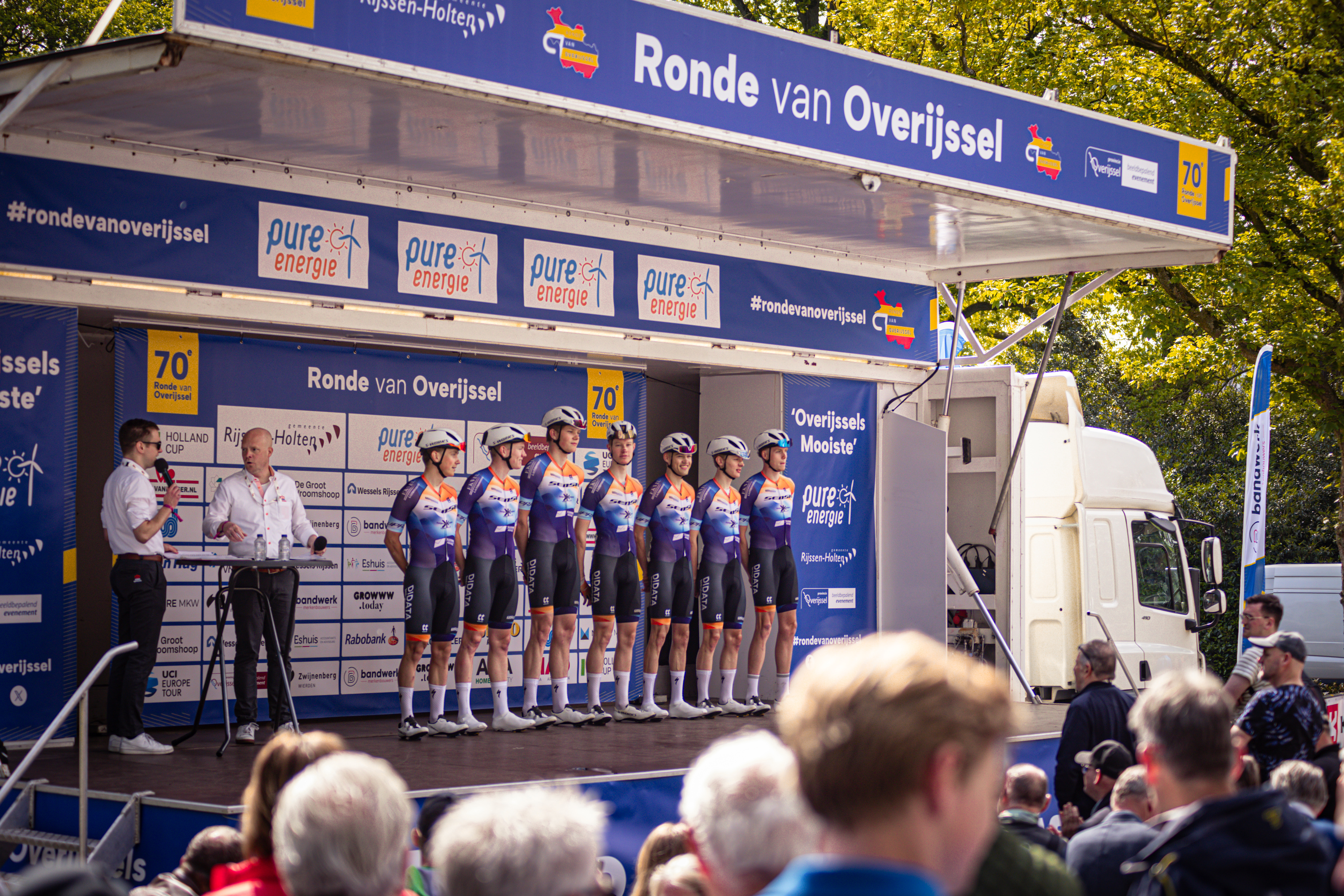 A group of athletes in front of a podium with the words Ronde van Overijssel on it.