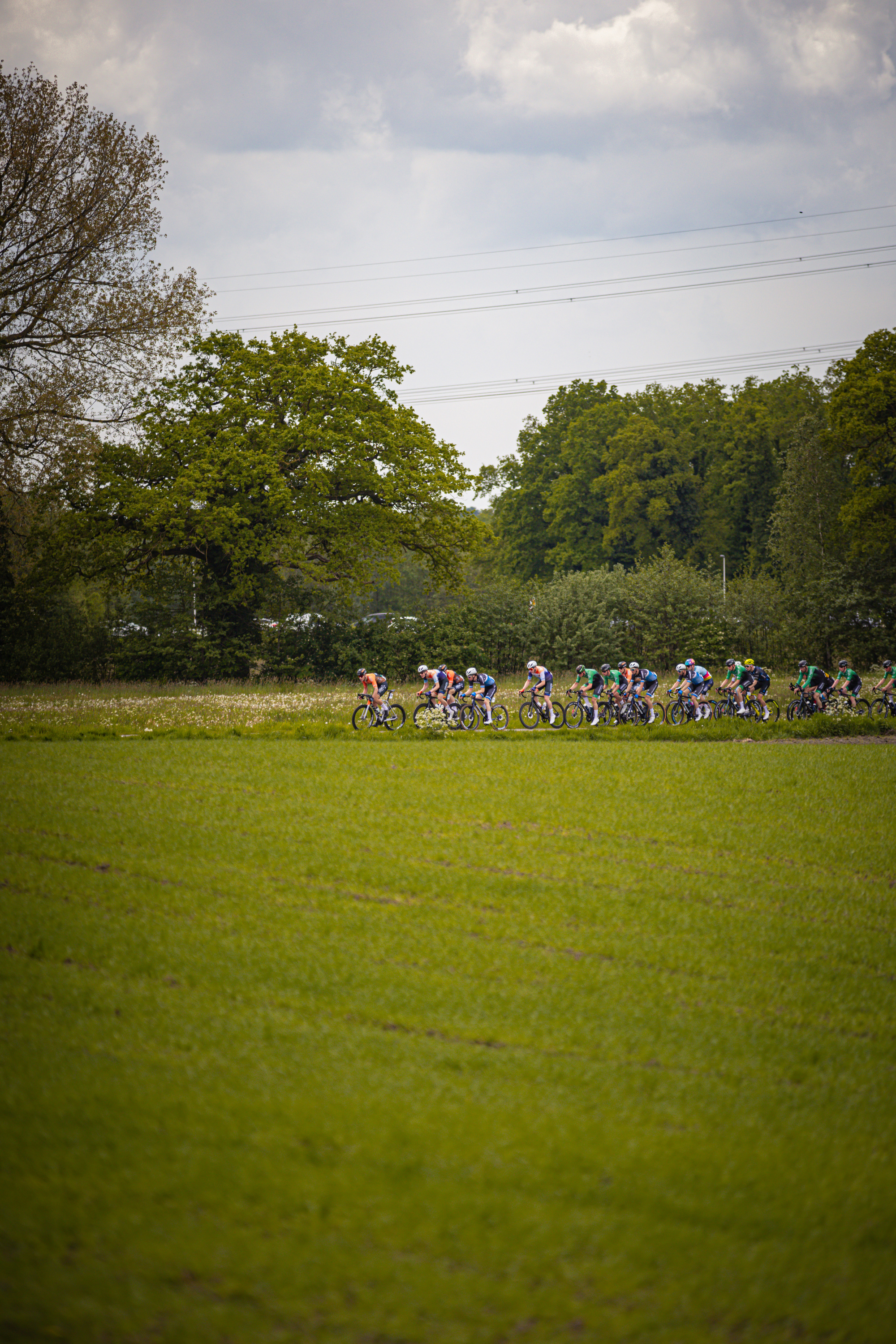 A group of cyclists are racing on a field during the Ronde van Overijssel in 2024.