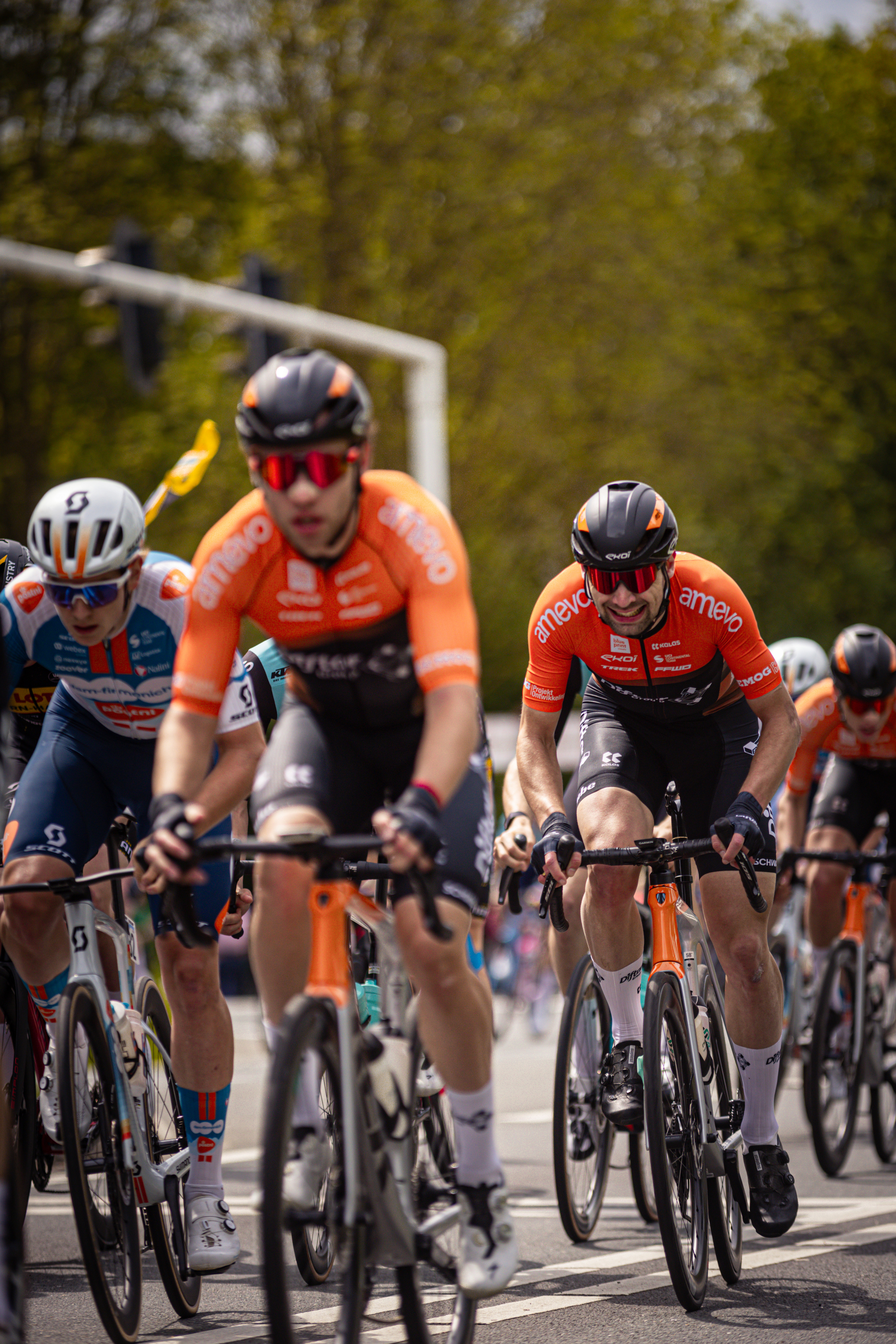 A group of cyclists are riding down the street at a race.