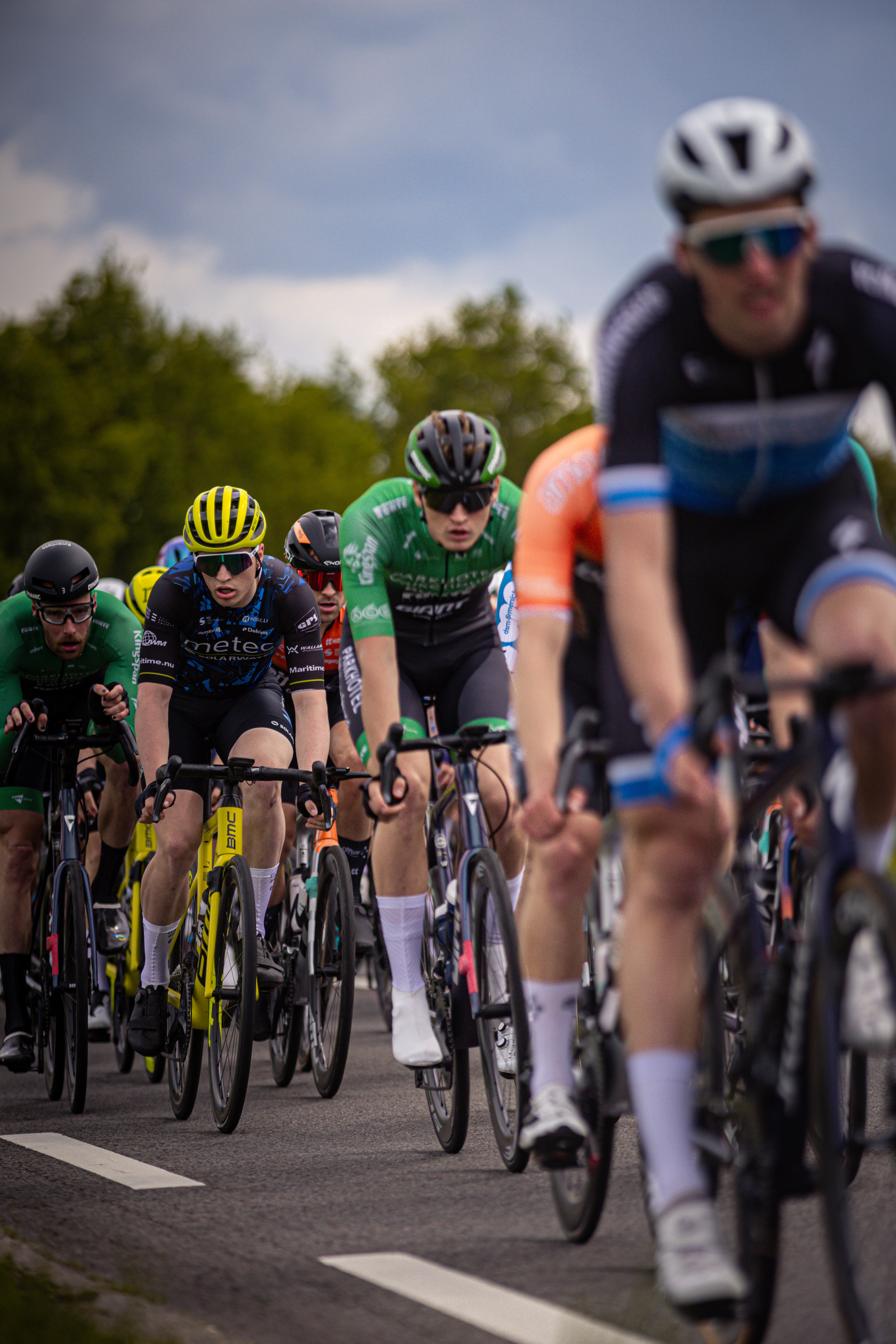 Several cyclists are wearing helmets as they race in a line.