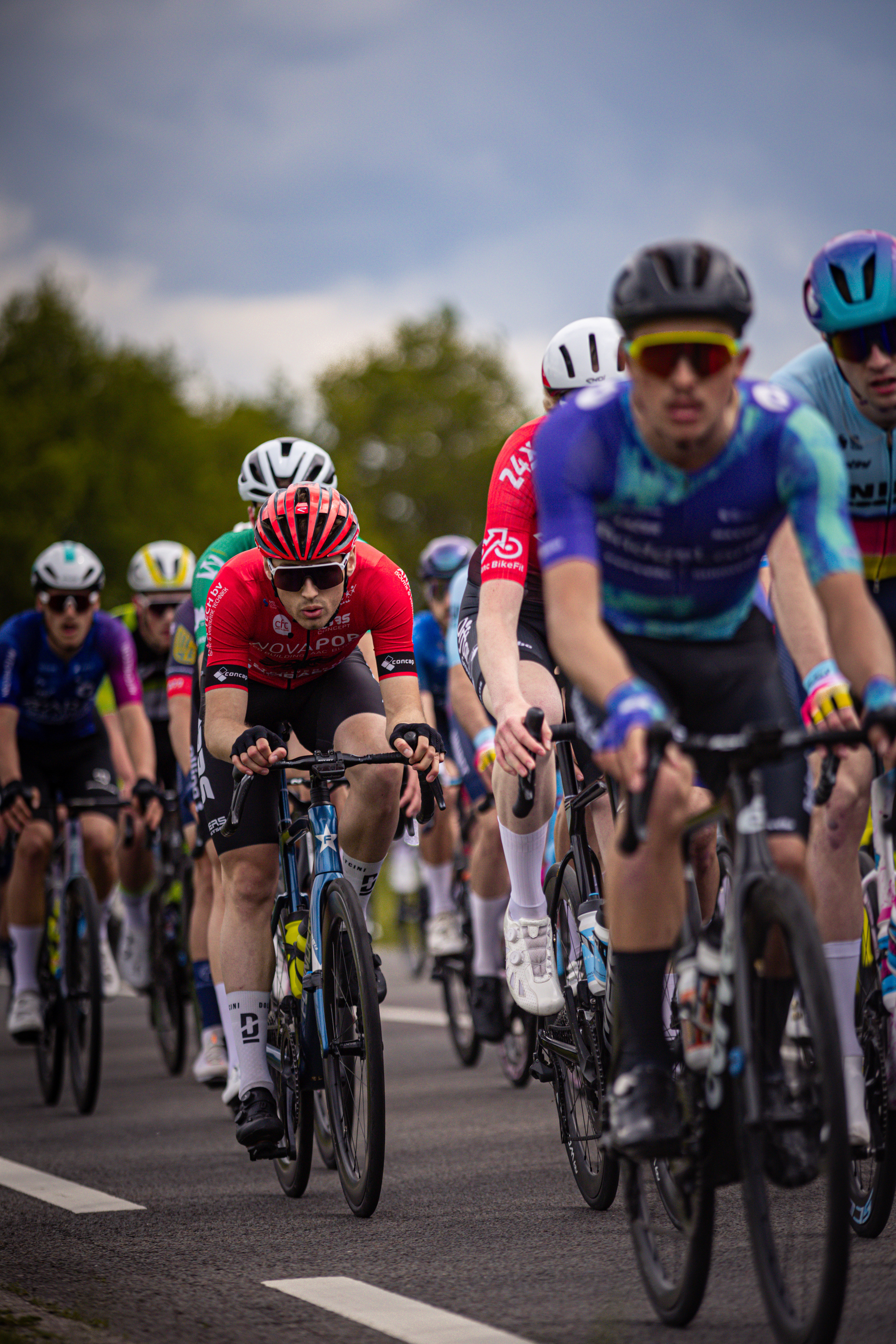 A group of cyclists participating in the Ronde van Overijssel race are riding closely together on a road.