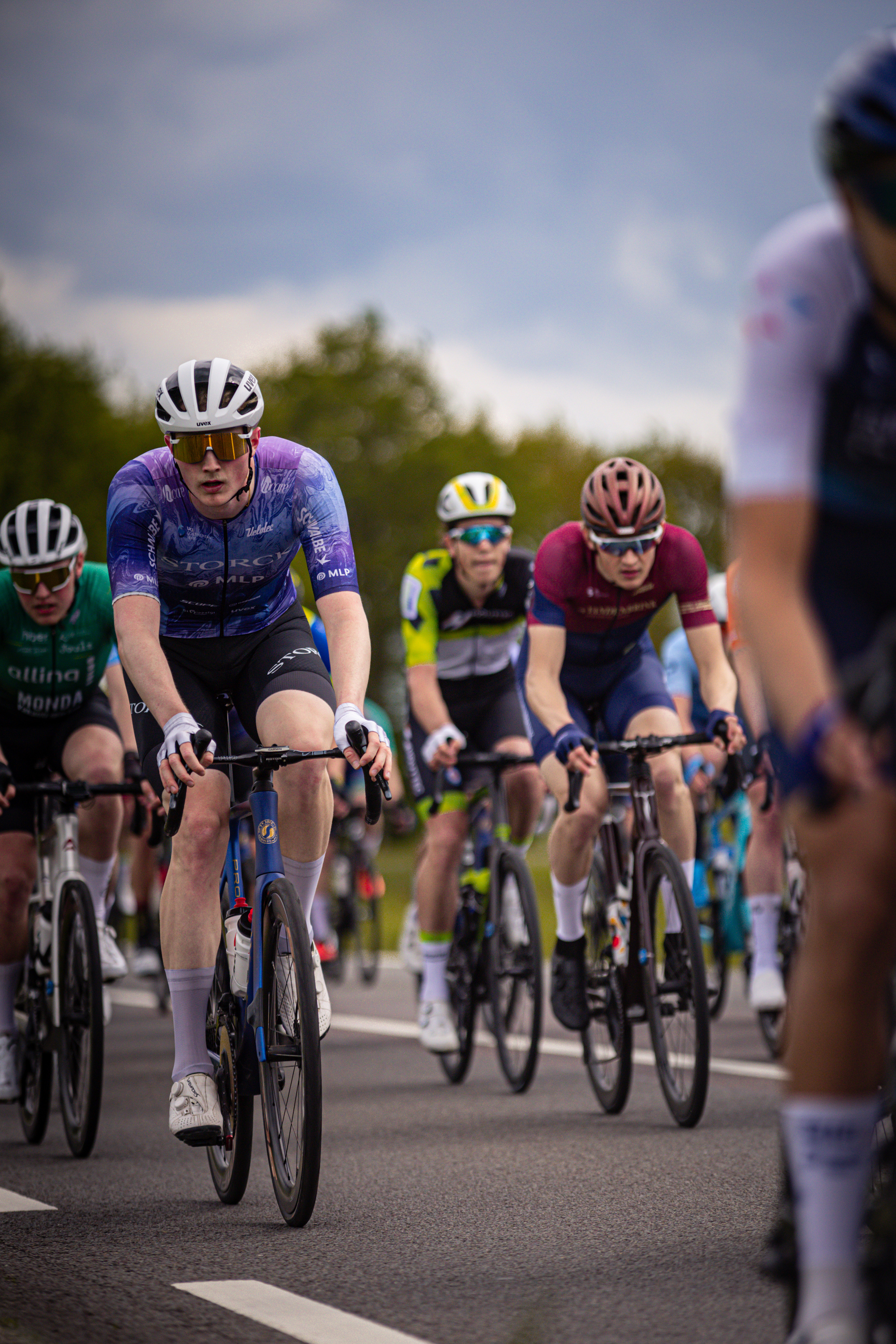 "Several cyclists are riding down a road in the Ronde van Overijssel cycling event".