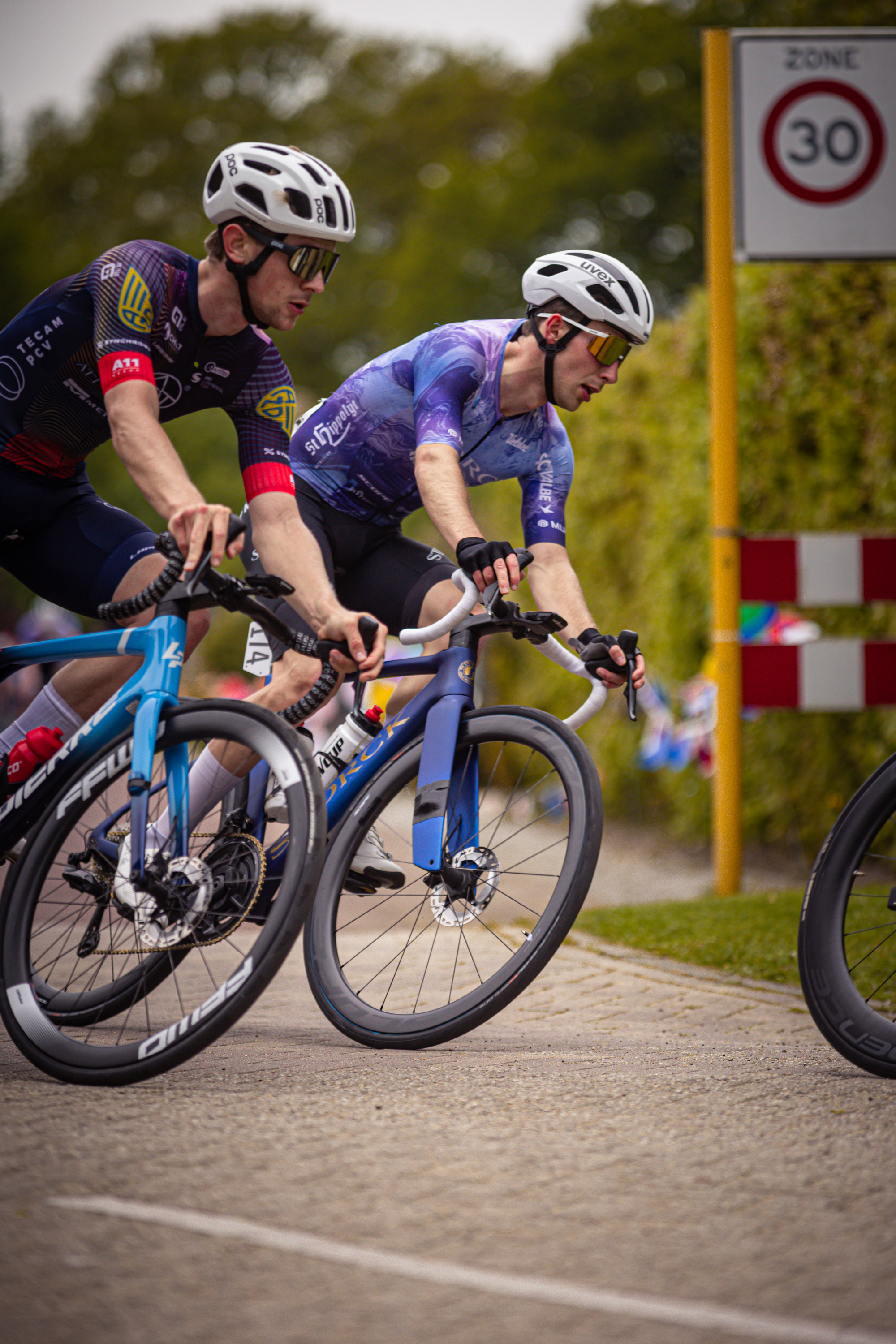 Two cyclists are racing in a race with the number 30 on the sign.