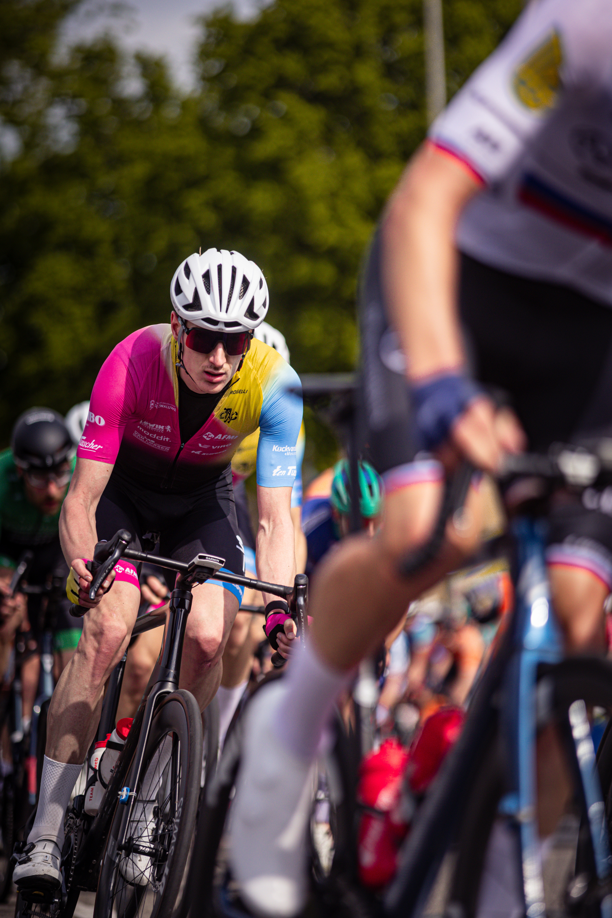 A group of cyclists racing in a race. The cyclist leading is wearing pink and black.