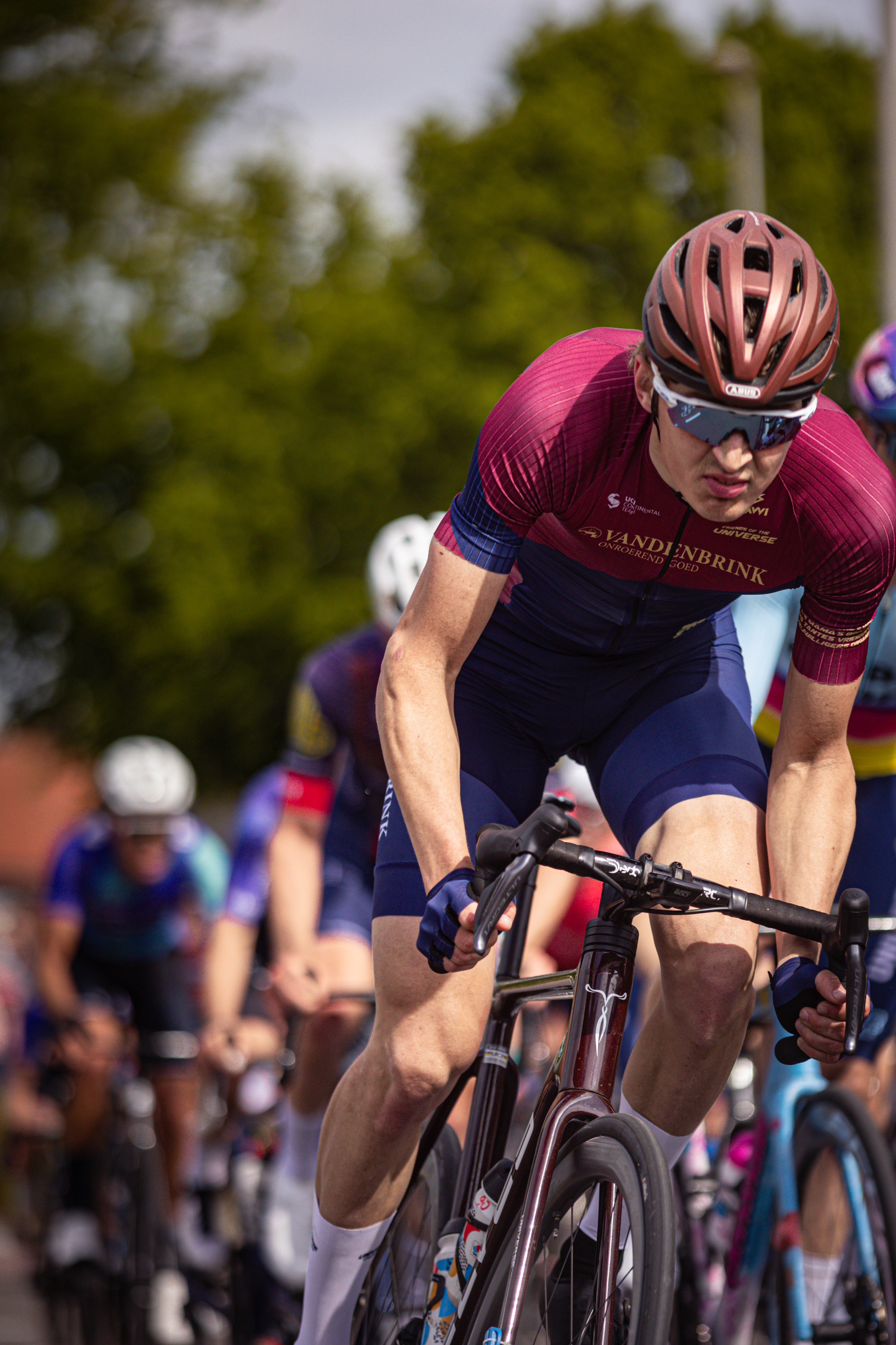 Bike race featuring cyclists riding on the track with one cyclist in blue and red.