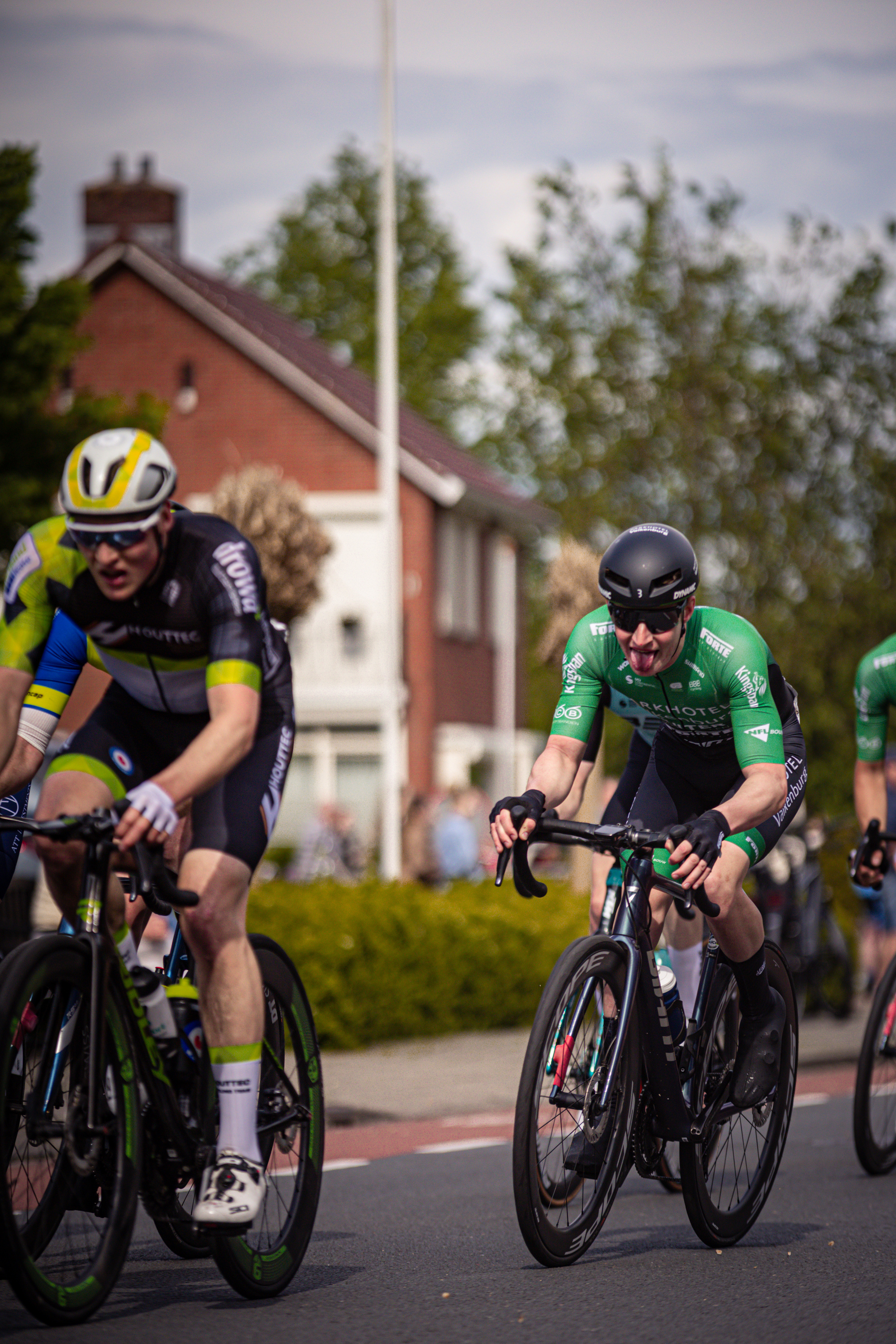 Three cyclists are racing in a group on the street during Ronde van Overijssel.