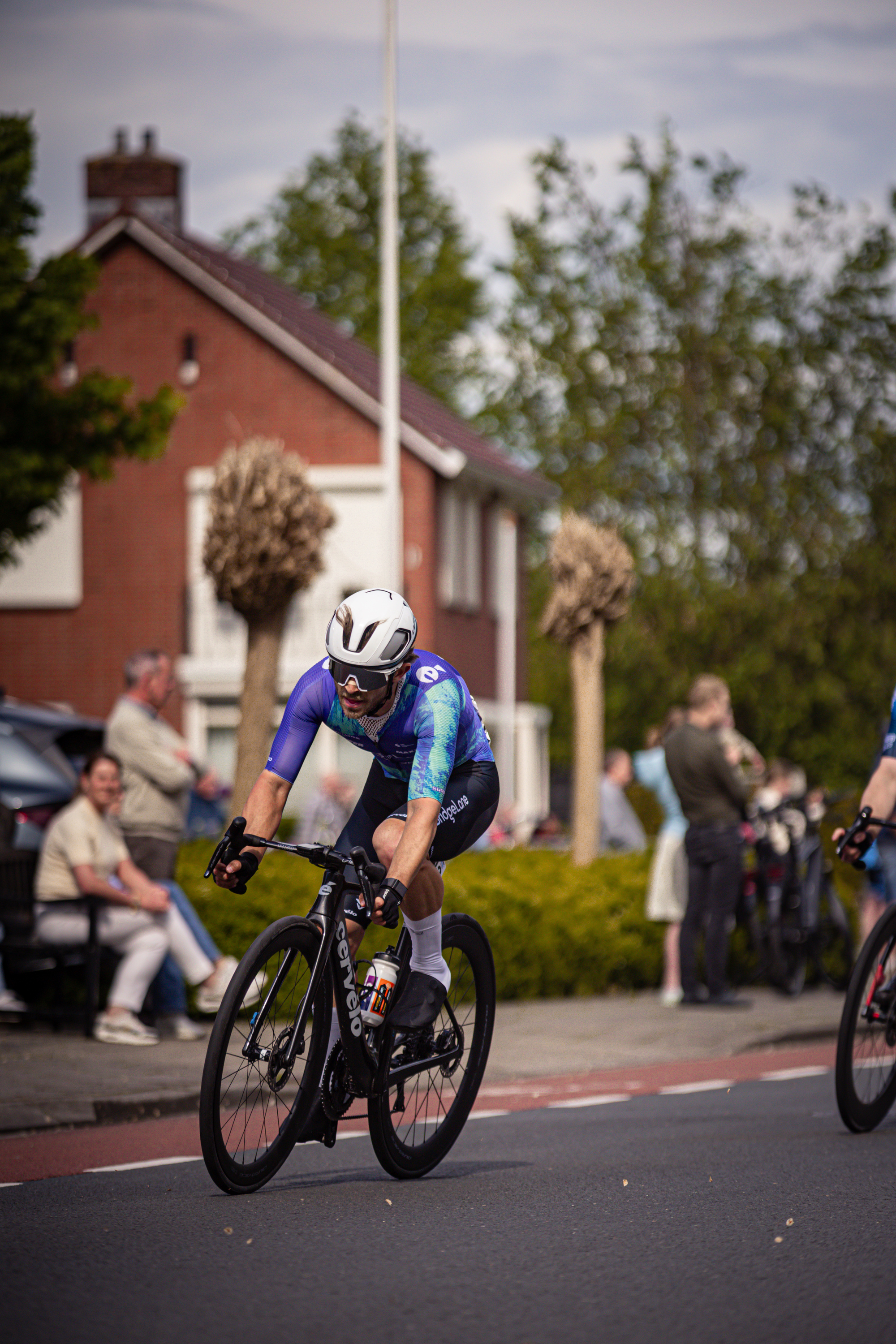 A cyclist wears a jersey of blue and white with the words "Ronde van Overijssel" on it.