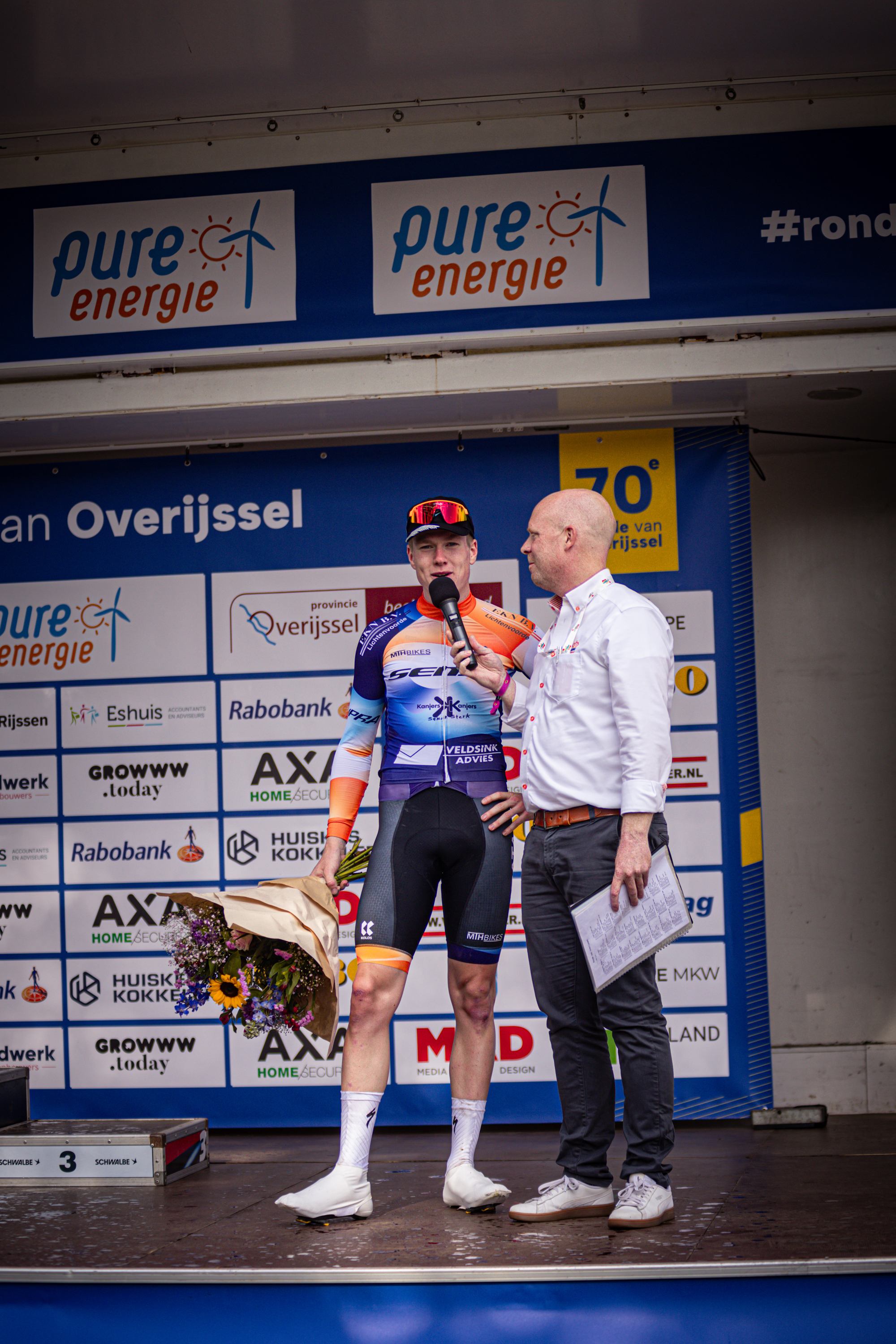 Two men standing on a stage at Ronde van Overijssel.