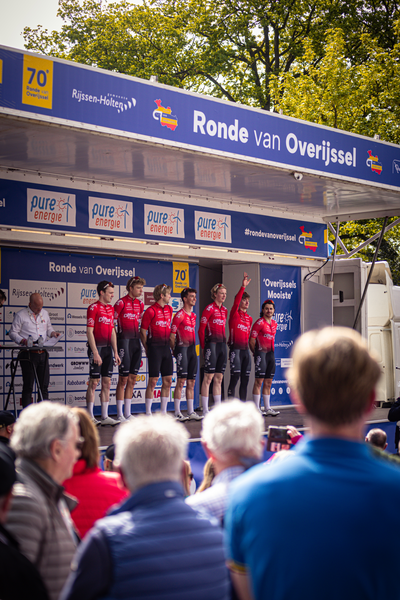 A group of cyclists on stage with a Rond van Overijssel banner.