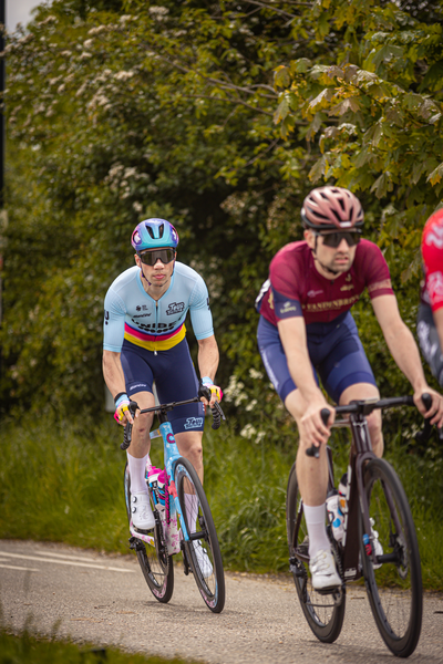 Two men in a race wearing blue and maroon riding bikes.