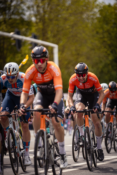 A group of cyclists are riding down the street at a race.