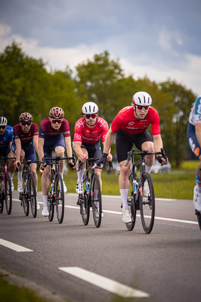 A cycling race with 5 men wearing different colored jerseys.