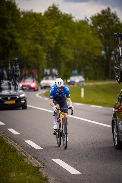 A man is riding a bike on a highway with cars in the background.