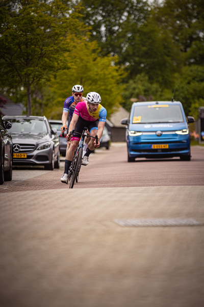 Two bicyclists race on a city street during the 2024 Ronde van Overijssel.