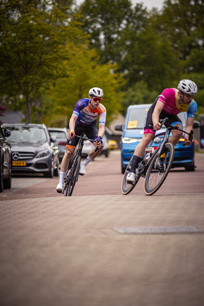 A man on a bicycle racing down the street with two other men in front of him.