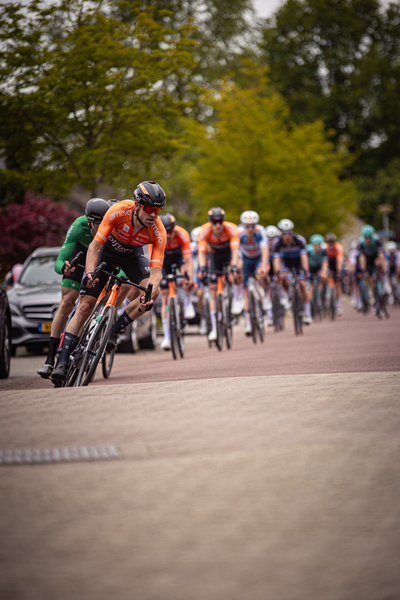 A cyclist participating in the Ronde van Overijssel race is part of a large group of cyclists.