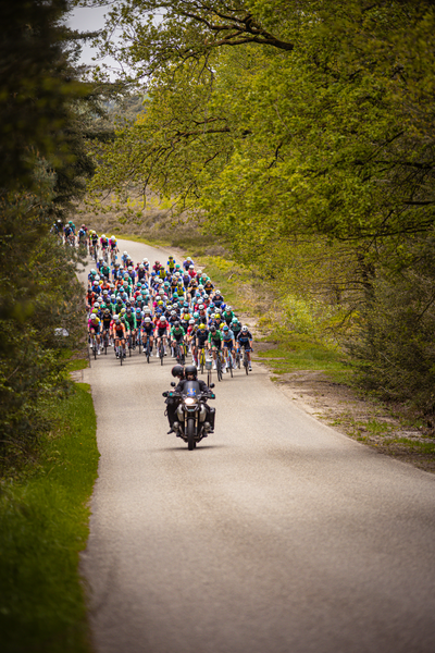 A cyclist is riding on a road with other cyclists behind them in the Ronde van Overijssel.