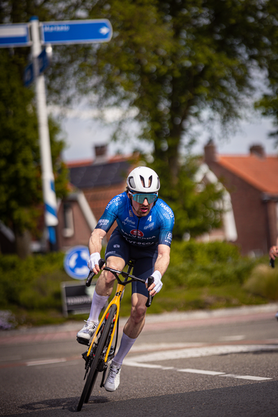 A man wearing a blue and white uniform is riding a yellow bike.