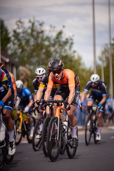 A group of people riding bikes in a race sponsored by the company Wielrennen.