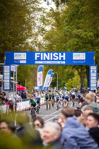 A group of cyclists crossing a finish line at the 2024 Tour de France in Overijssel.