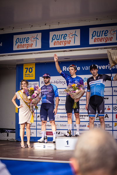 Group of athletes celebrating their victory on stage with flowers and blue jerseys reading 2024.