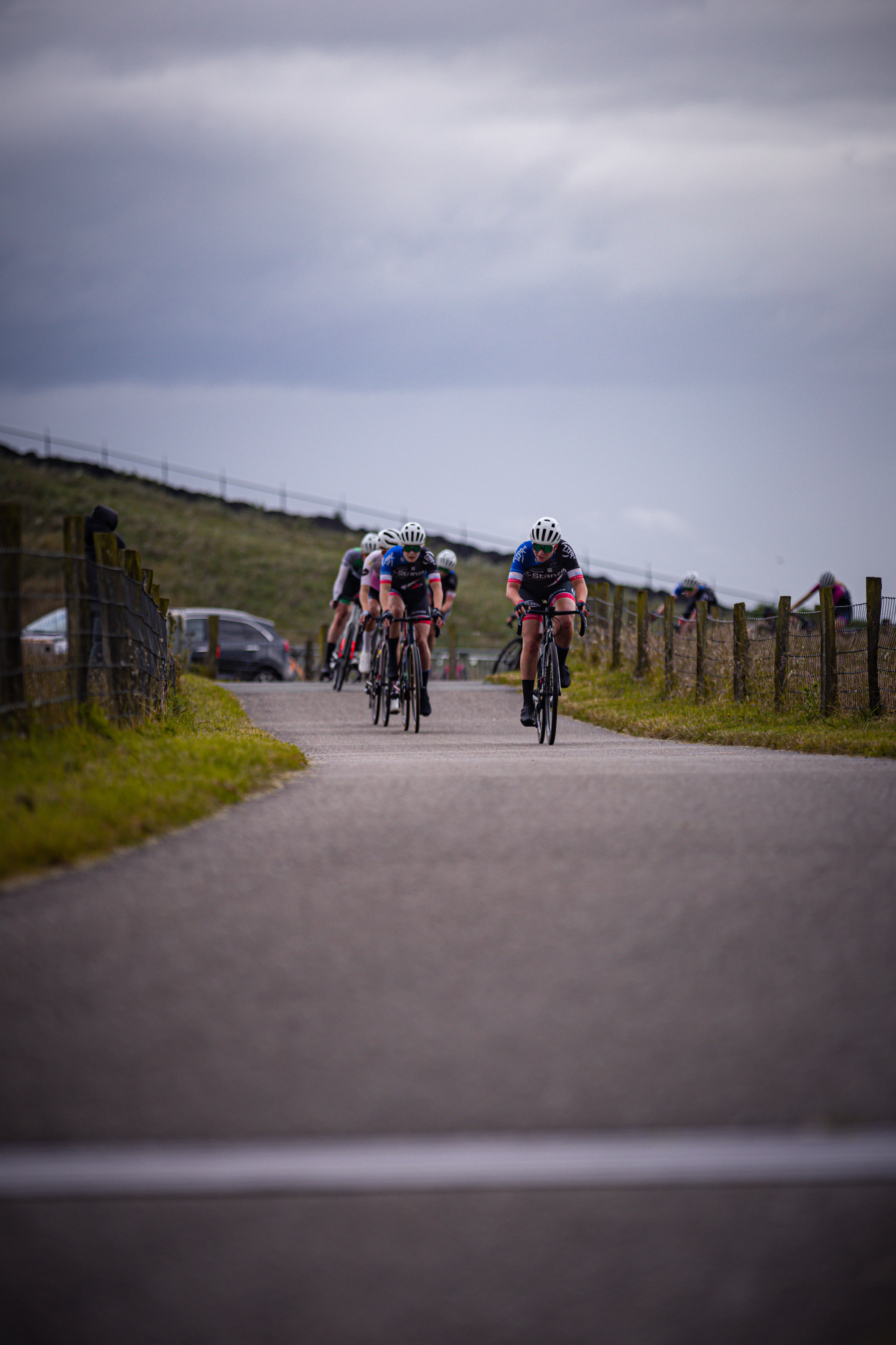 Four cyclists in blue and black suits are riding on a road.