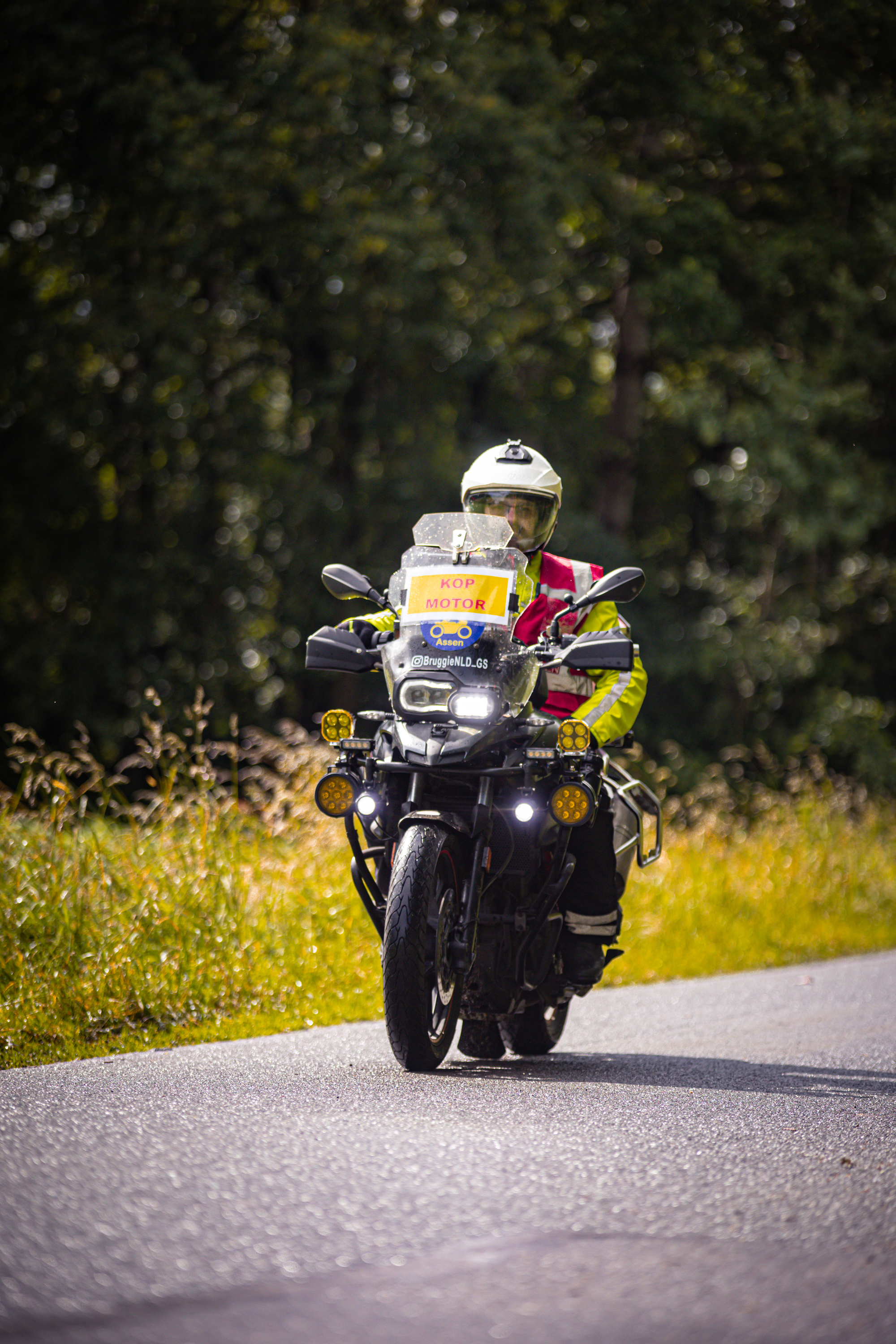 A man is wearing a helmet and riding a motorcycle down the road.