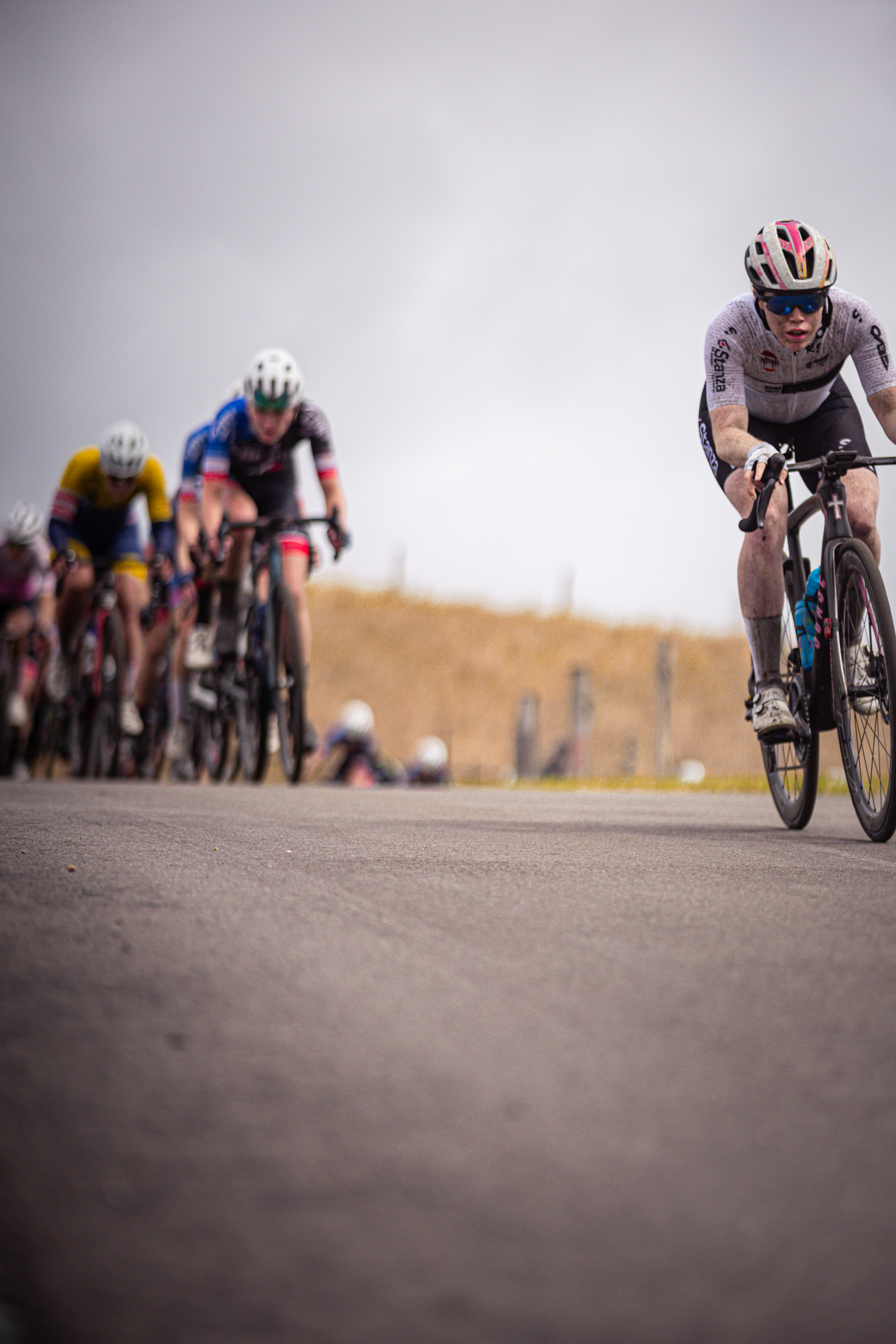 A group of cyclists are racing down the road at the Nederlands Kampioenschap.