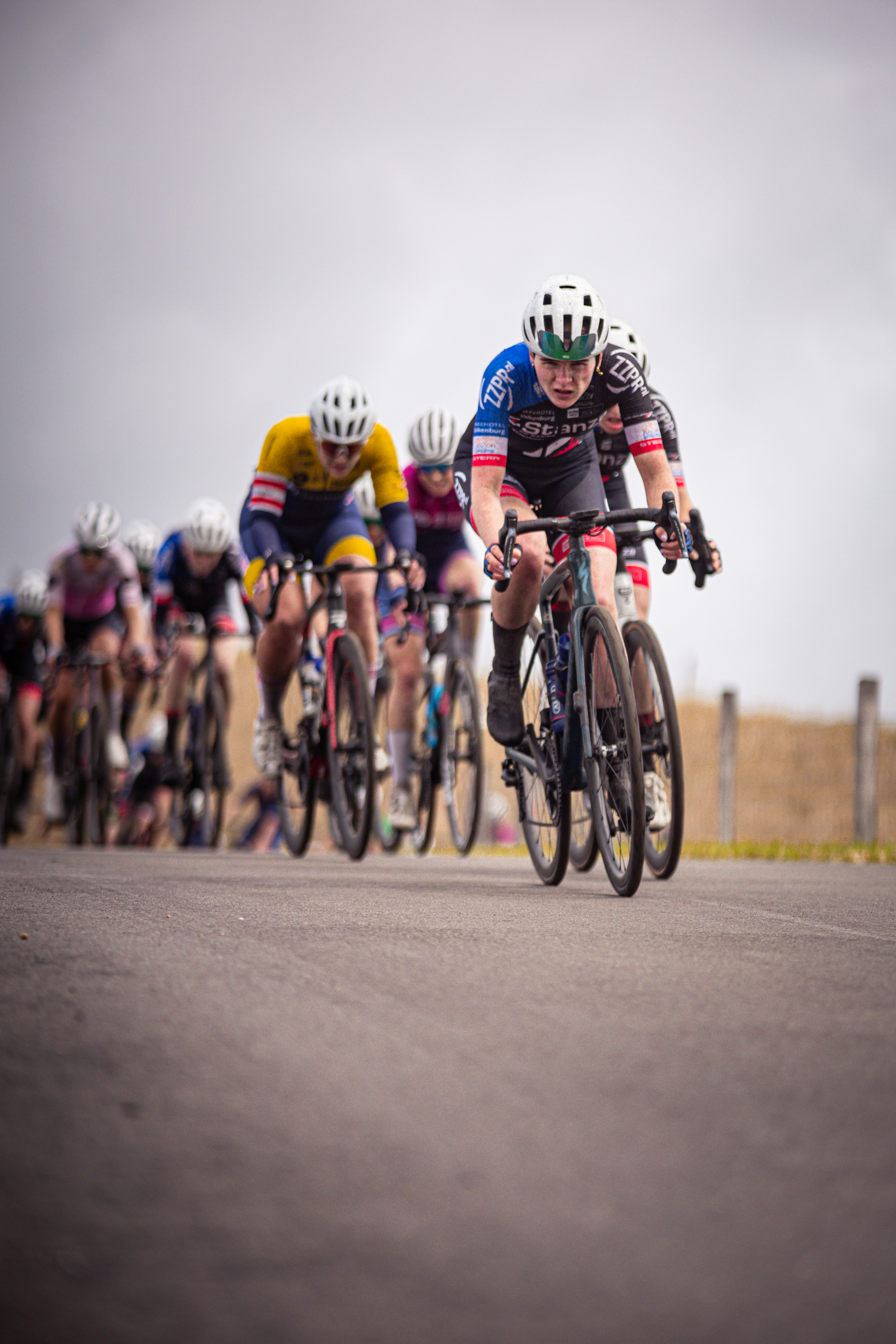 A group of cyclists race on a road as they compete in the Nederlands Kampioenschap.