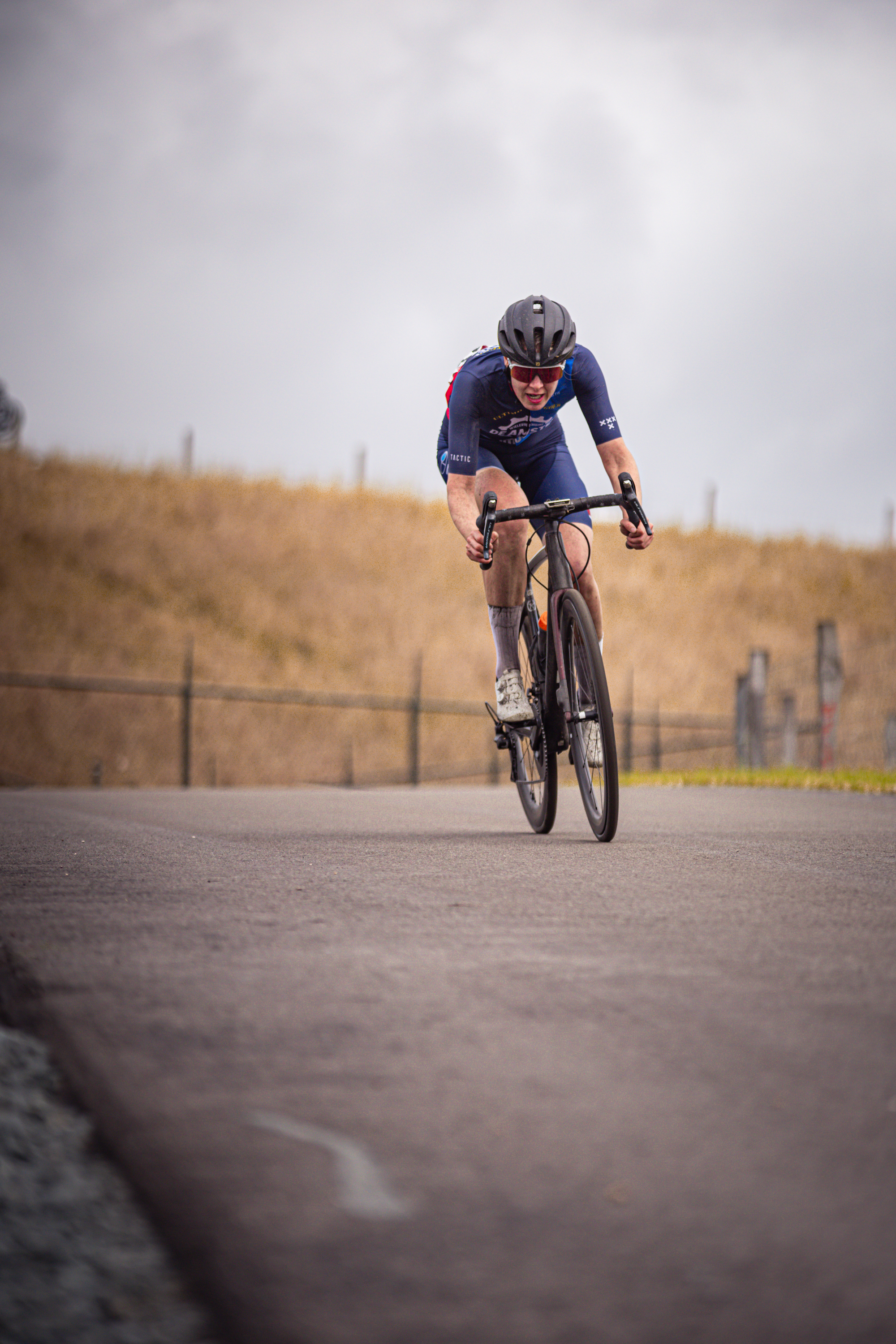 A man wearing a blue suit is riding a bike. The photo was taken during the Nederlands Kampioenschap.