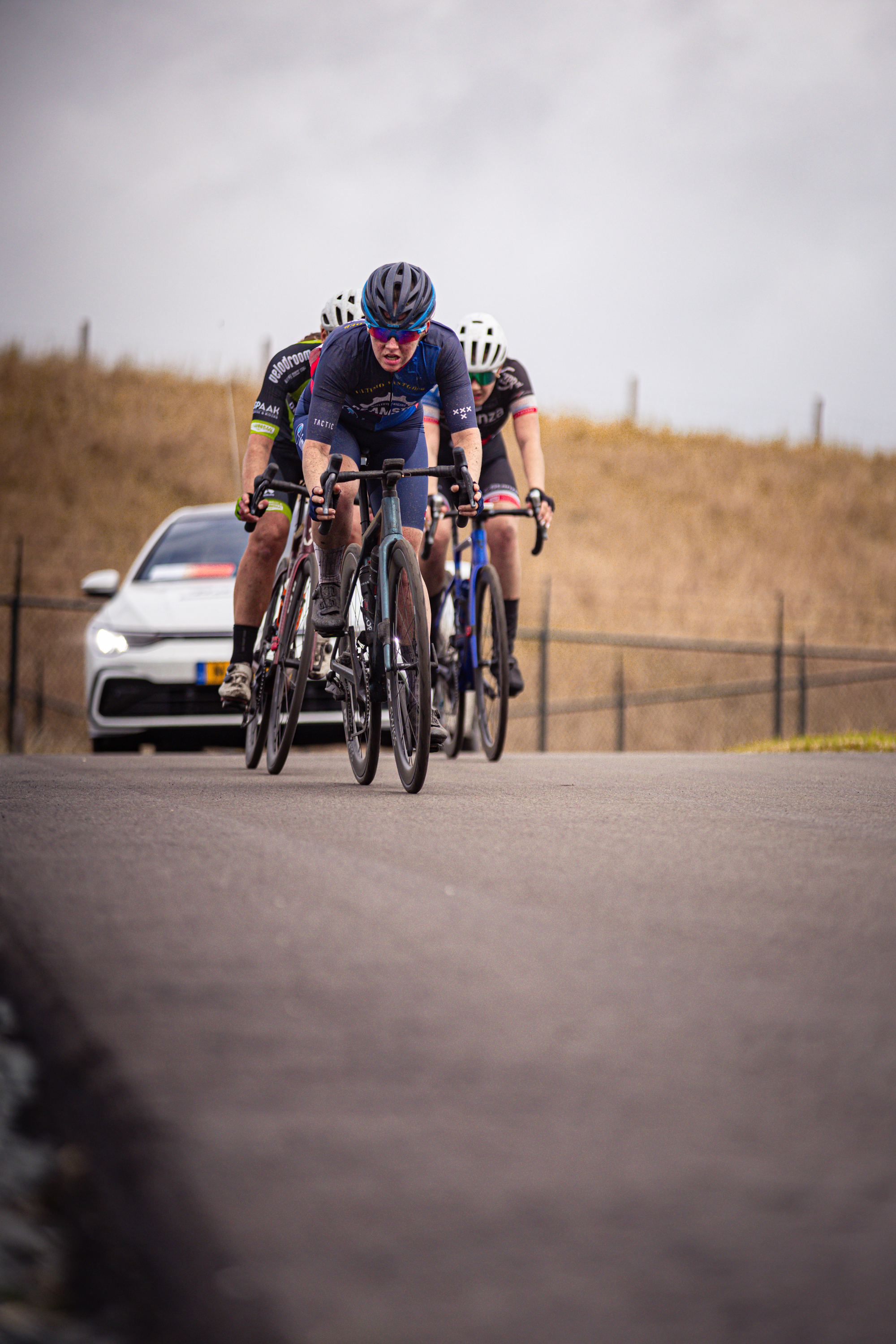 The cyclists on the road are participating in the Nederlands Kampioenschap, a women's cycling race.