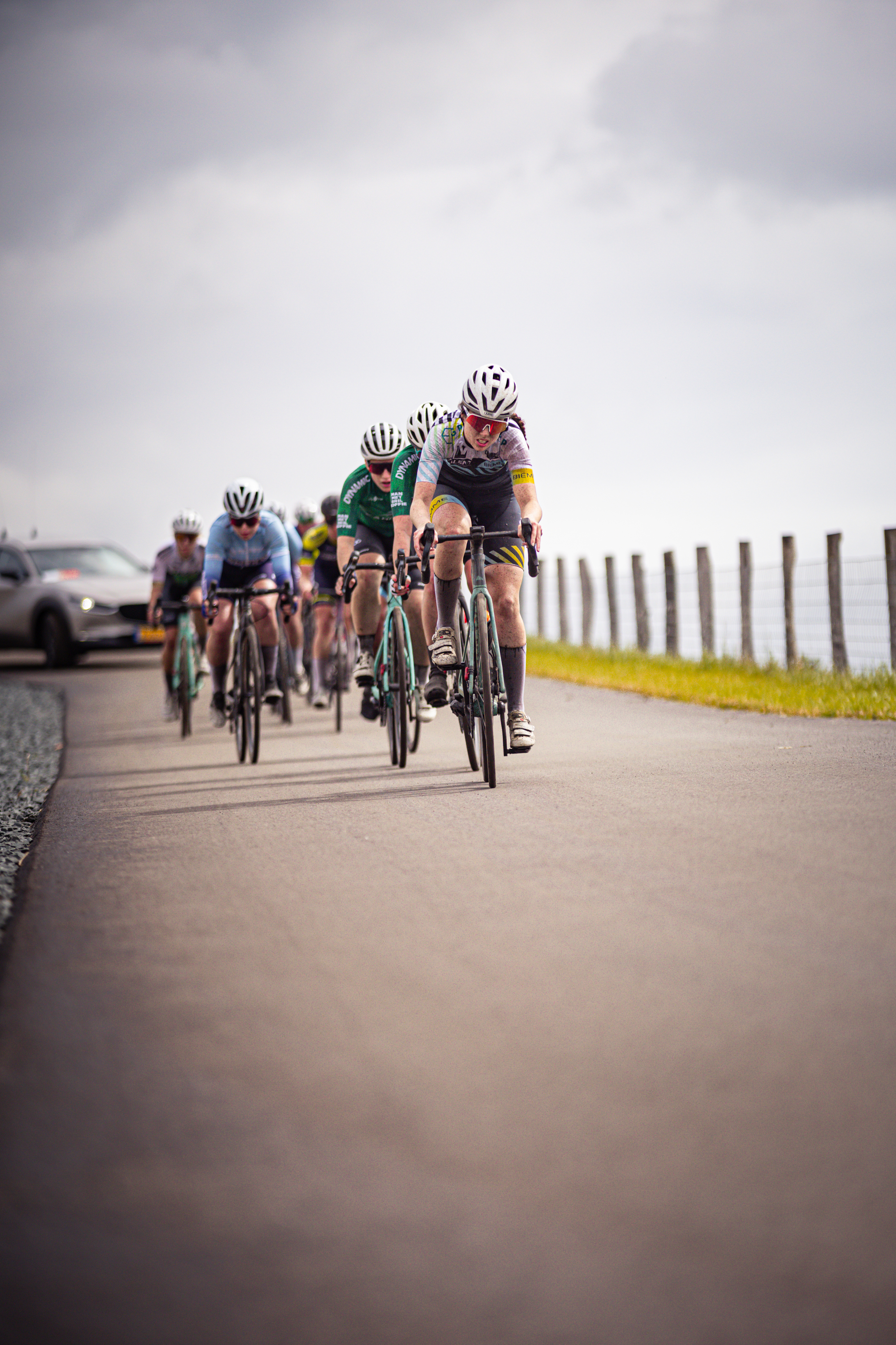 A cyclist is riding in the front of a group on bicycles. They are wearing a black jersey with the number 2 on it.