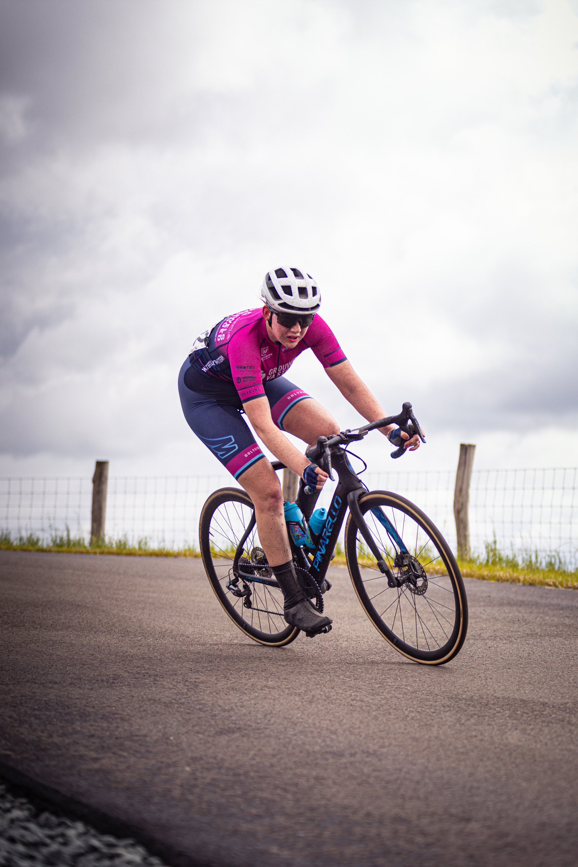 A woman wearing a helmet riding a blue and black bicycle.