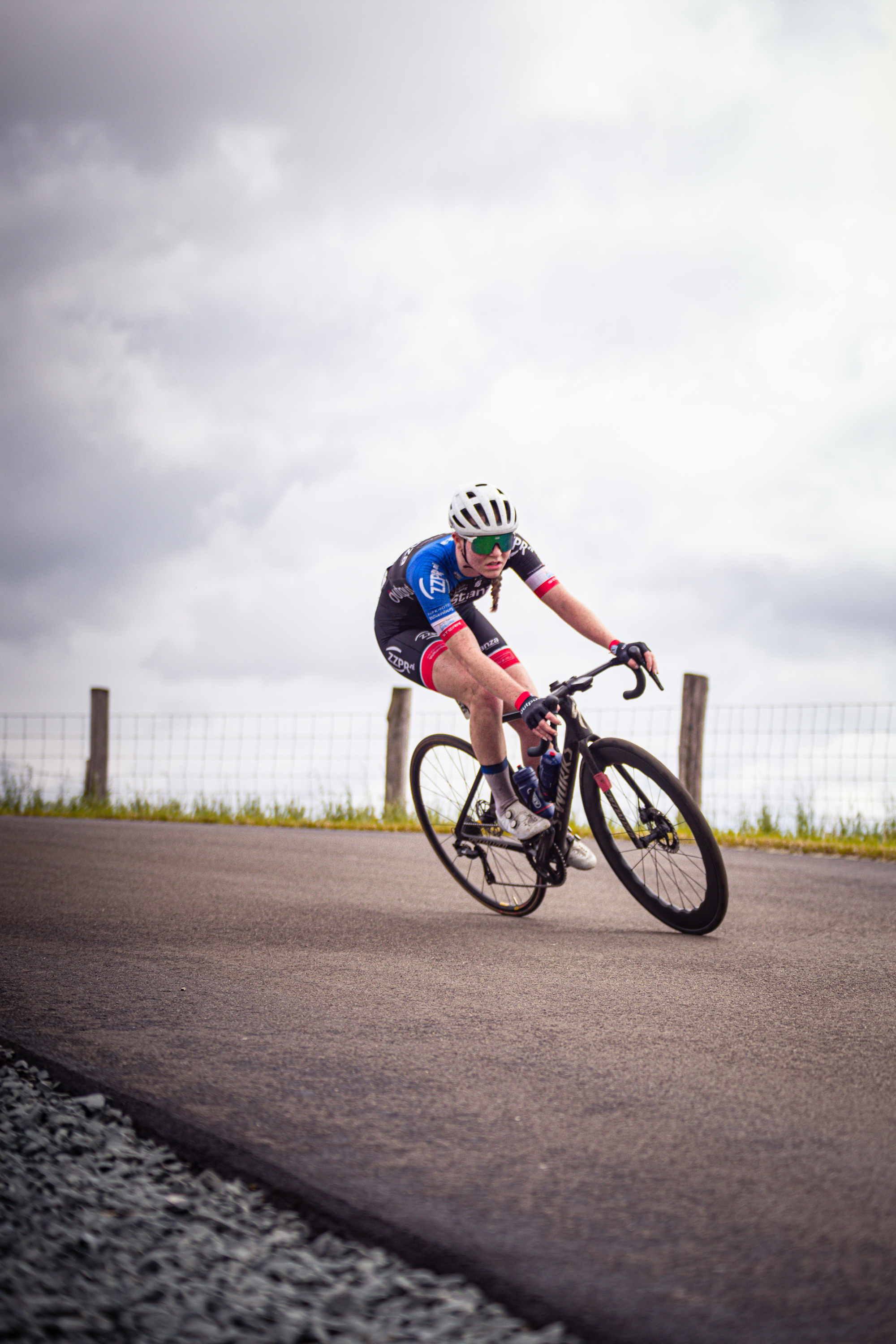 A woman wearing a jersey with the number 1 is riding her bike on a road.