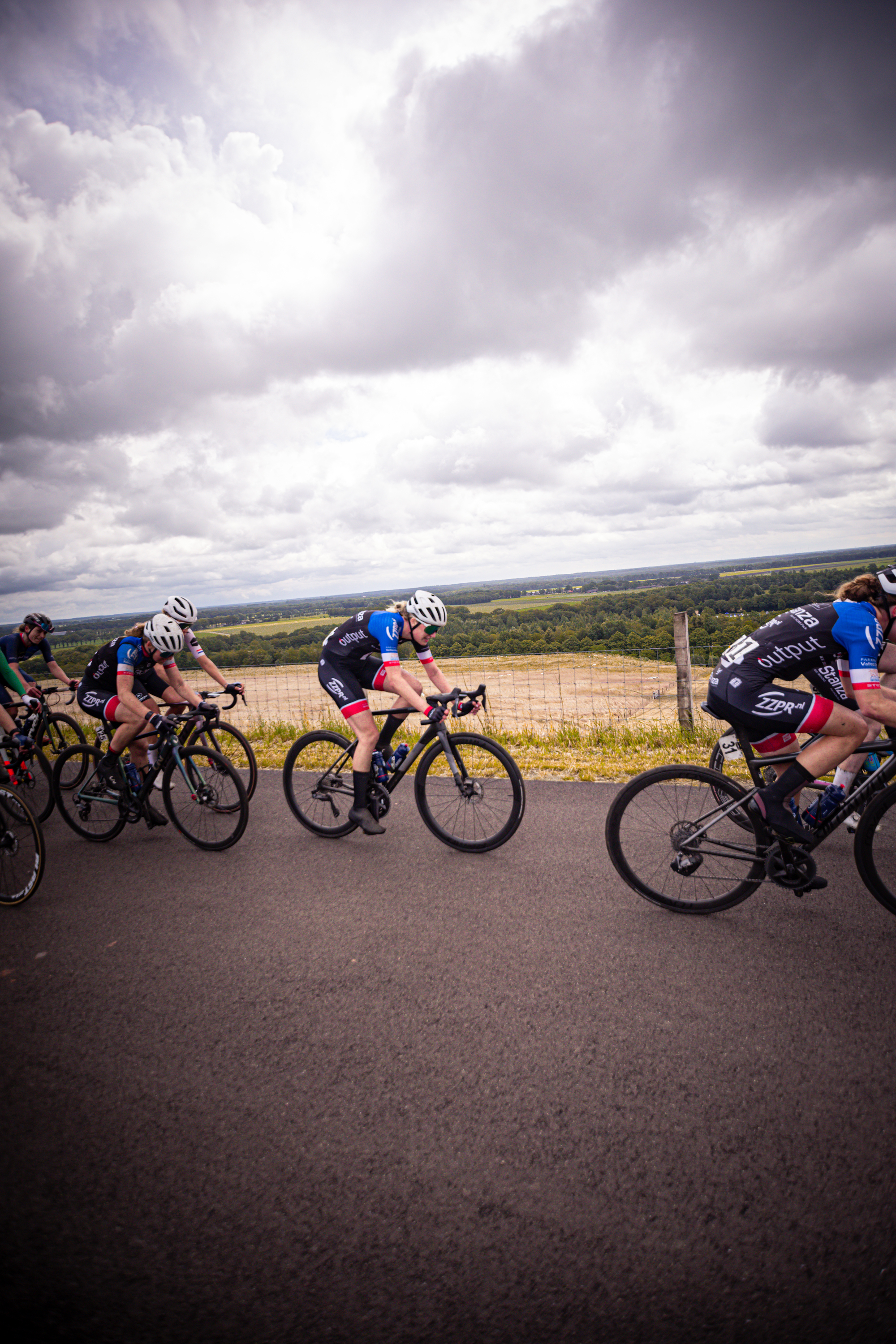 Group of cyclists on the road, one wearing a blue and white uniform with ZC on it.