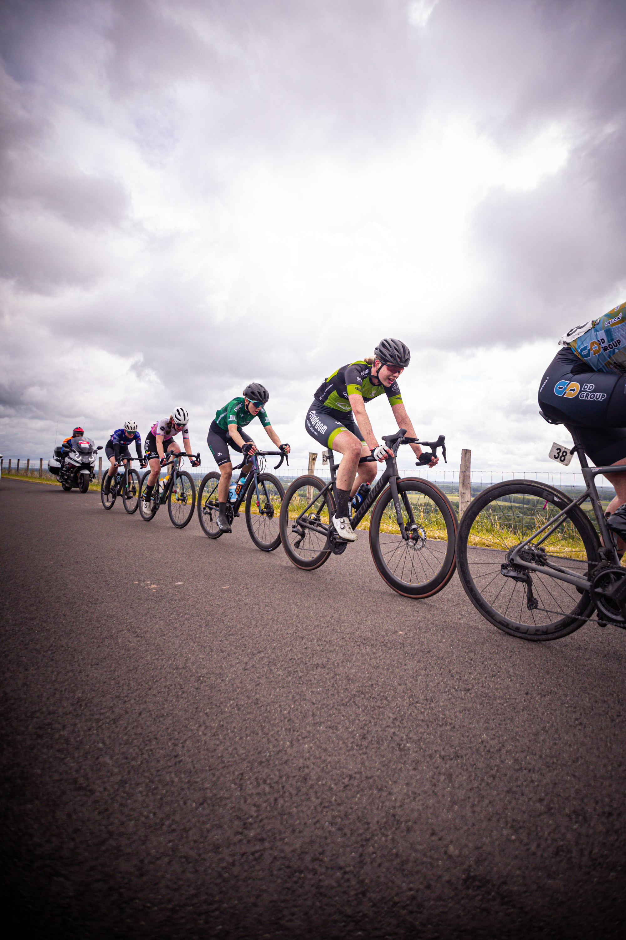 A group of cyclists wearing black and white helmets compete in the Nederlands Kampioenschap.