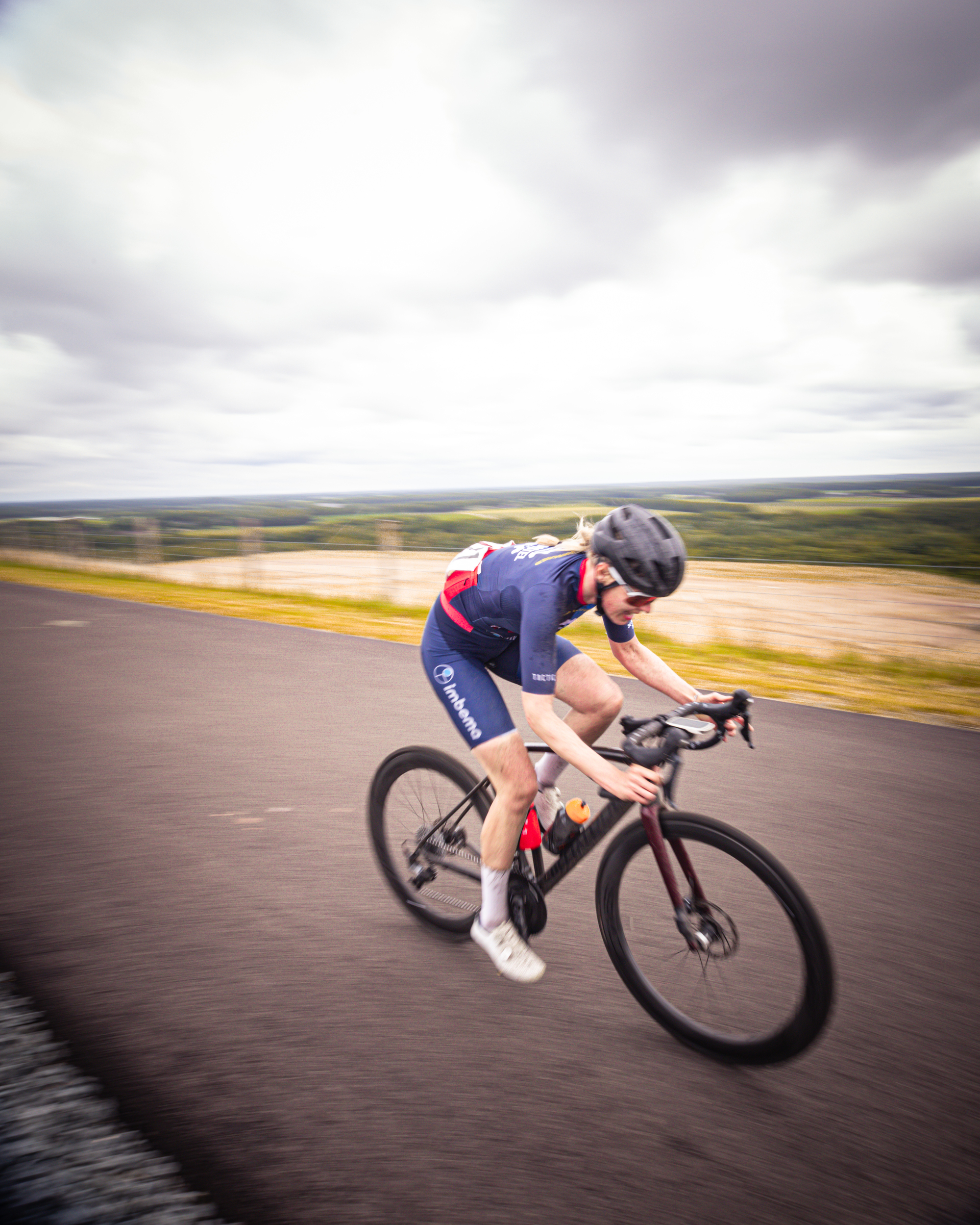 A woman wearing a blue and red shirt riding a bicycle.