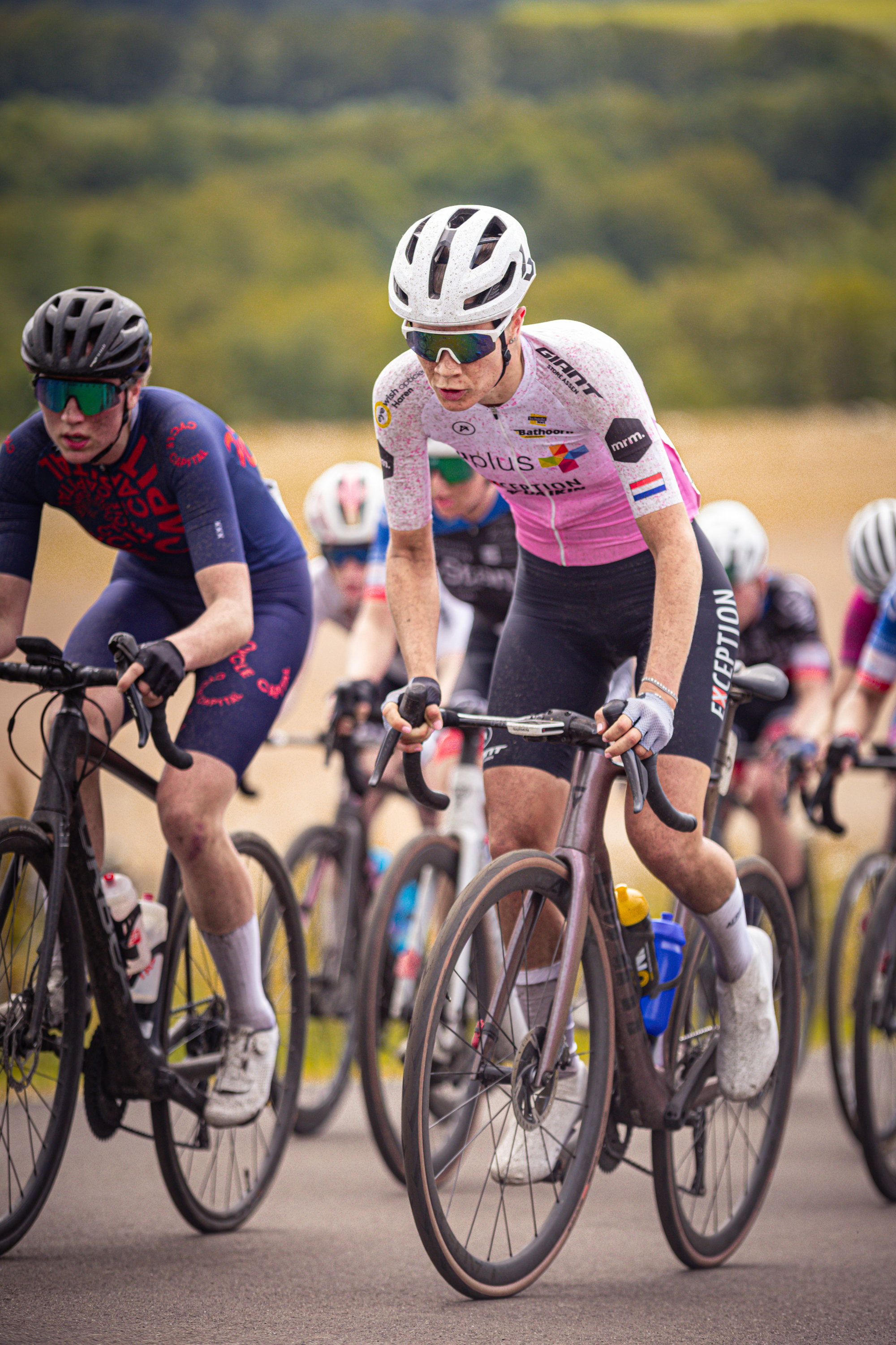 A group of cyclists, with the most prominent wearing a shirt saying "Dames Elite ZC", on a road.