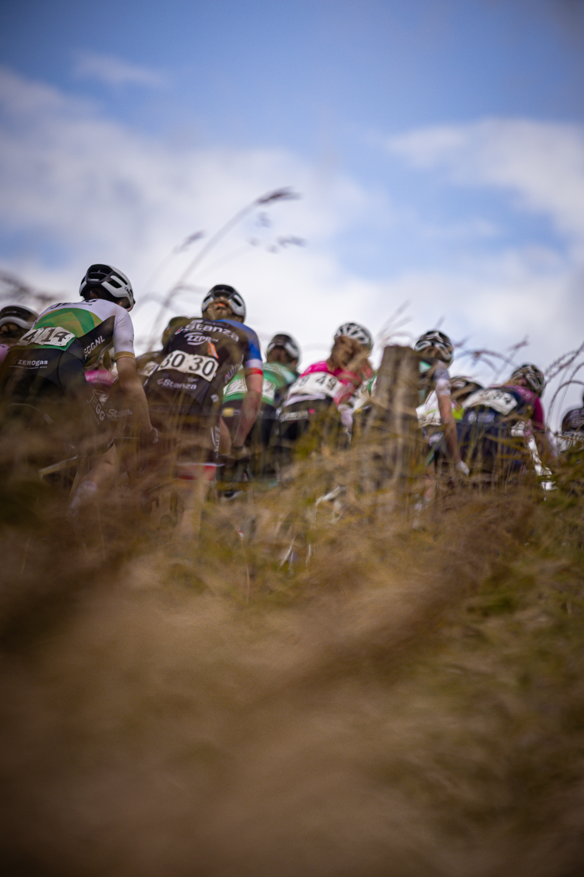 A group of cyclists wearing helmets and jerseys with numbers 10 and 15 ride their bikes on a hill.