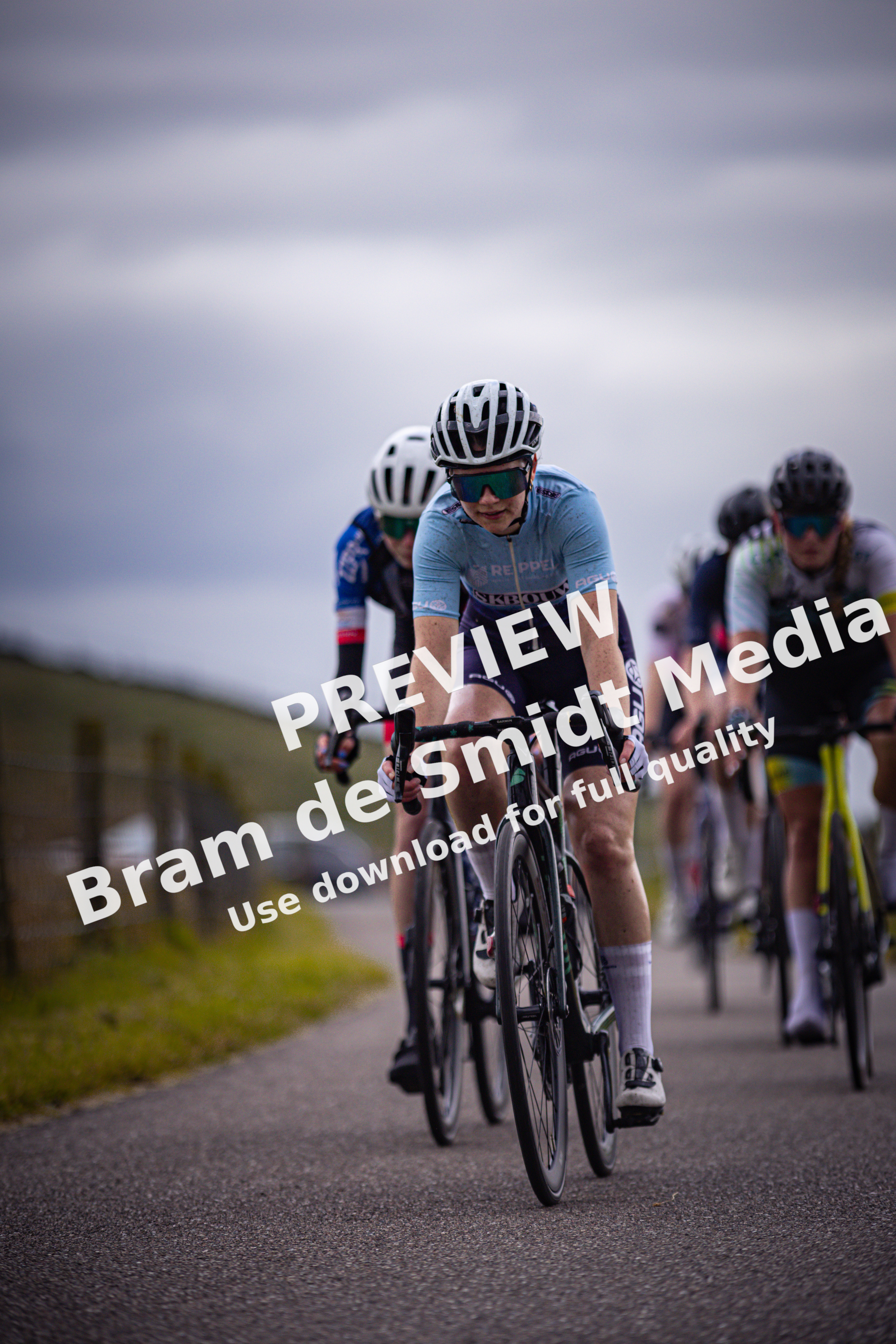 A group of cyclists race down the road as they compete in the Nederlands Kampioenschap.