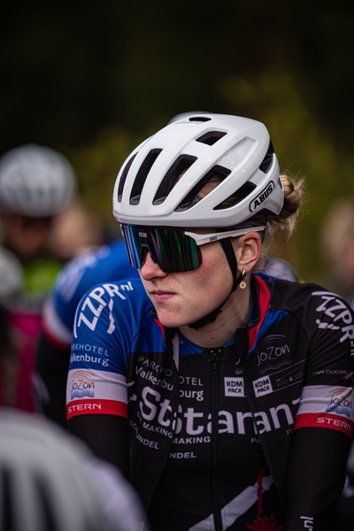 A woman wearing a black and white jersey with Stichting on it is looking off to the side.