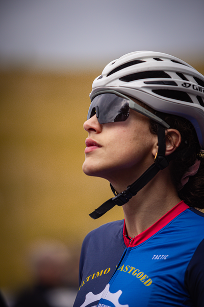 A young woman in a blue shirt reading Nederlands Kampioenschap 2024 wearing a black and white helmet standing next to a man.