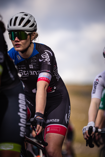 A female cyclist wearing a black jersey with the word "Stanx" on it is riding her bike.