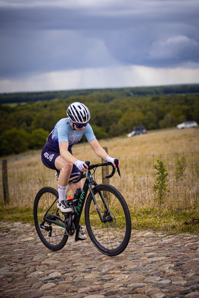 A person in a blue shirt and a white helmet is riding a bicycle down a path.