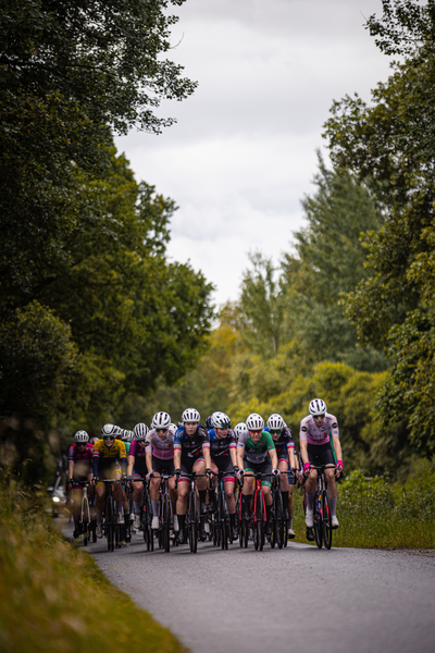 Dames Elite ZC cycling team wearing pink and blue uniforms are riding bicycles.