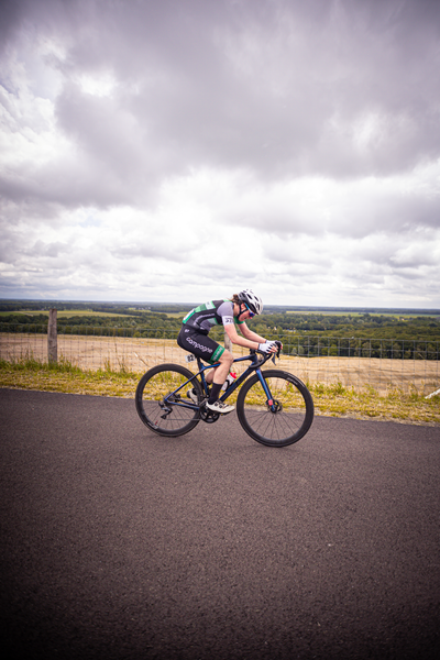 A cyclist wearing a white helmet races on a track at the Nederlands Kampioenschap.