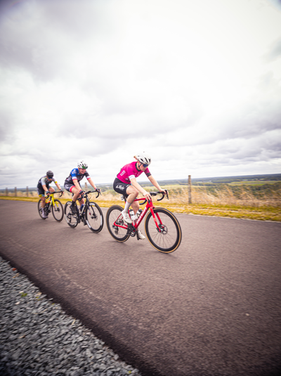 Four cyclists on a road with one in the lead, number 1.