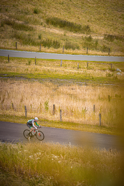 A cyclist wearing number 2 is riding down a rural road.