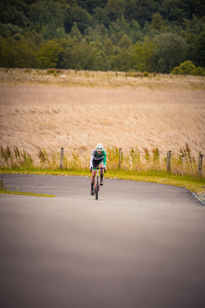 A woman on a bicycle is wearing a green and black jersey.